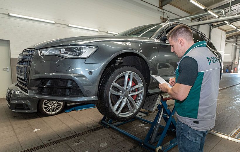 DEKRA-Prüfer inspiziert ein Auto auf der Hebebühne